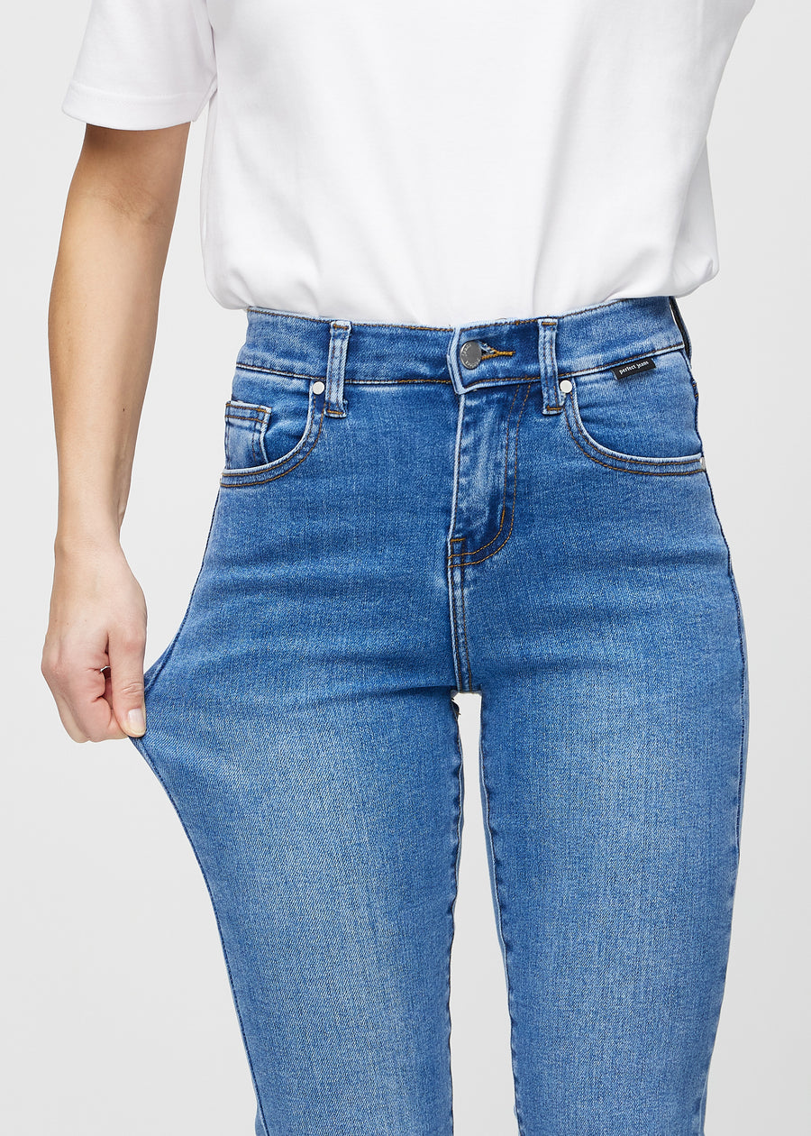 Slim-Jeans für Damen in Blau, Farbe Rivers. Ein Model zieht am Jeansstoff am Oberschenkel, um den Stretch zu zeigen.