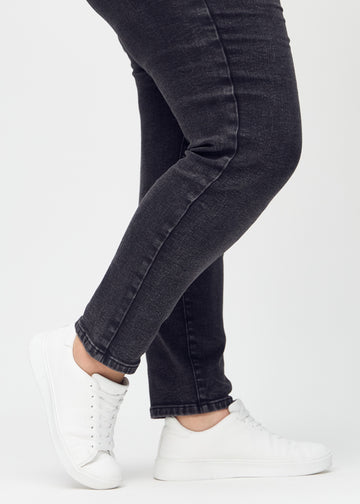 Slim-Jeans für Damen in Dunkelgrau, Farbe Shadows. Nahaufnahme an den Knöcheln eines Plus-Size-Models, um die Passform am Beinabschluss zu zeigen.