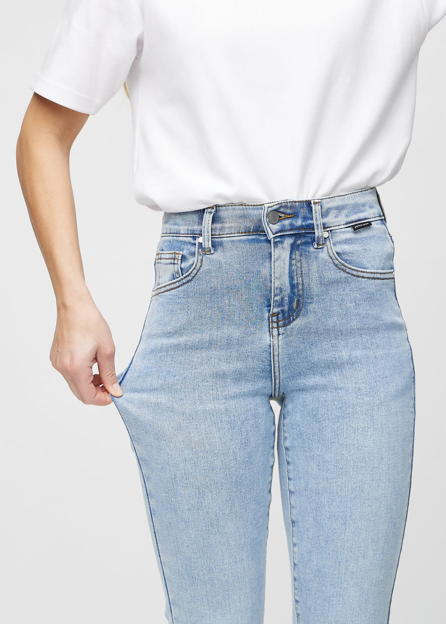 Slim-Jeans für Damen in Hellblau, Farbe Waves. Ein Model zieht am Jeansstoff am Oberschenkel, um den Stretch zu zeigen.