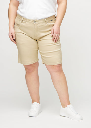 Beige regular middle shorts, Modellname Gazelles, die gerade am Bein entlang fallen und knapp über dem Knie enden, an einem Plus-Size-Model von vorne gesehen.
