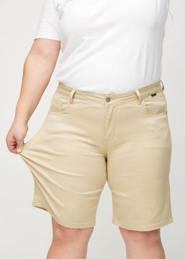 Das Plus-Size-Model zieht die Shorts am Oberschenkel auseinander, um den Stretch zu zeigen.