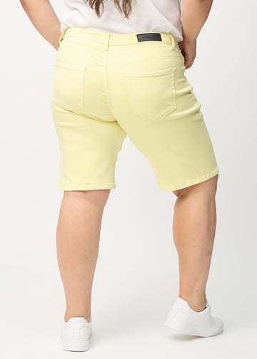 Hellgelbe regular Middle Shorts von hinten an einem Plus-Size-Model gesehen, sodass man das ganze Produkt sehen kann.