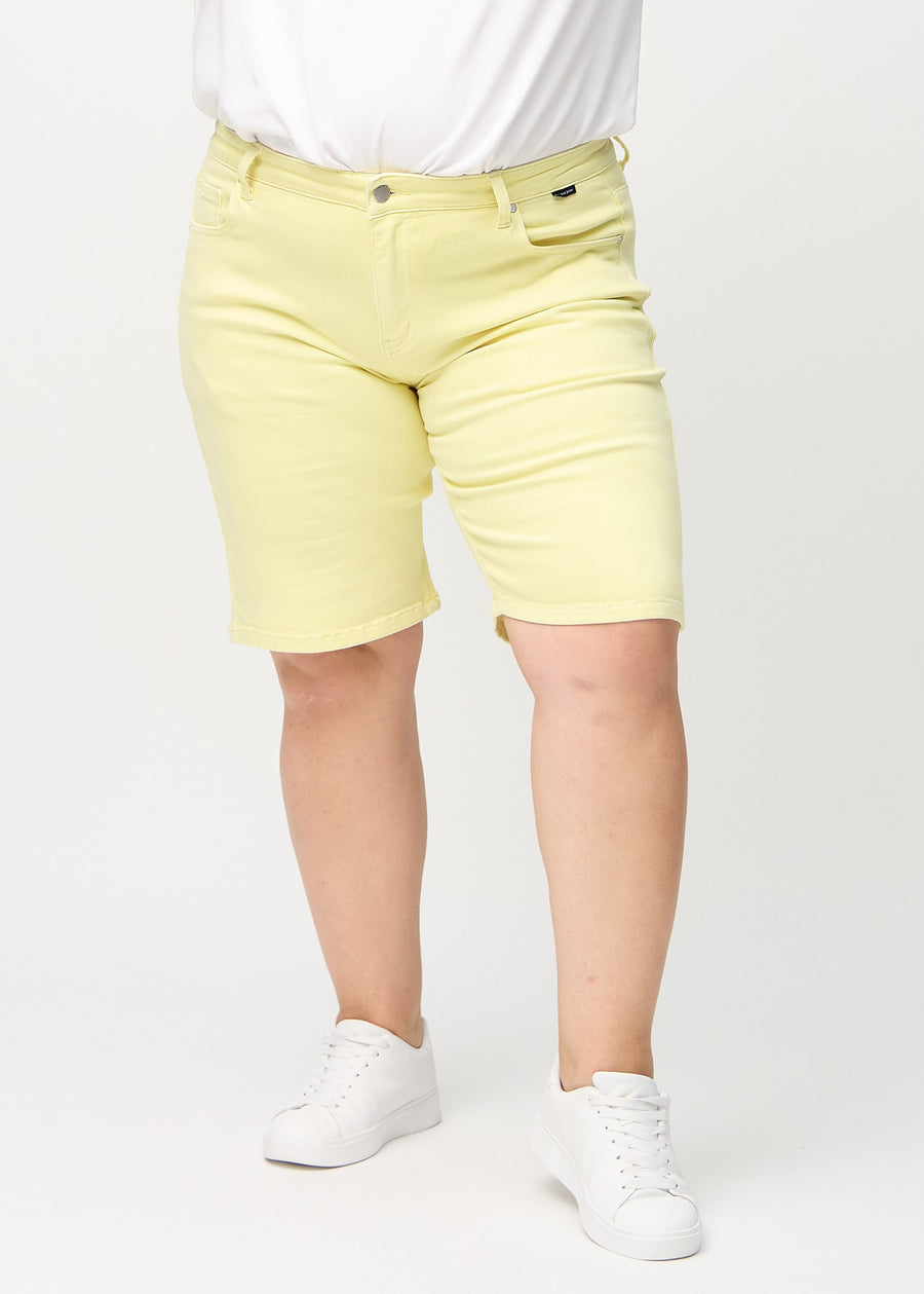 Hellgelbe regular Middle Shorts, Modellname Lemonades, die gerade am Bein entlang fallen und knapp über dem Knie an einem Plus-Size-Model enden, von vorne gesehen.
