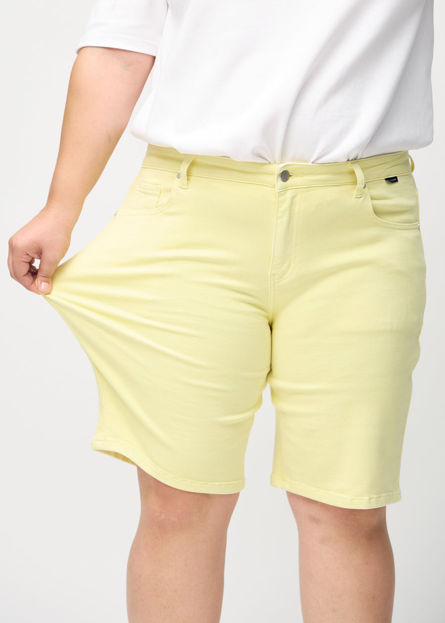 Das Plus-Size-Model zieht die Shorts am Oberschenkel auseinander, um den Stretch zu zeigen.