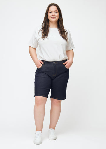 Ganzkörperbild eines Plus-Size-Models in tief dunkelblauen Denim-Shorts für Damen in der Farbe Midnights mit Regular-Passform.