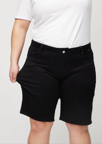 Das Plus-Size-Model zieht die Shorts am Oberschenkel auseinander, um den Stretch zu zeigen.