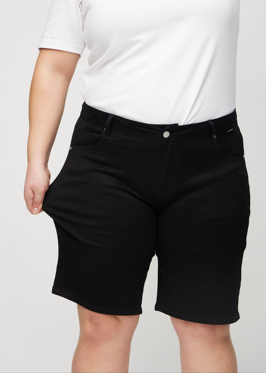 Das Plus-Size-Model zieht die Shorts am Oberschenkel auseinander, um den Stretch zu zeigen.