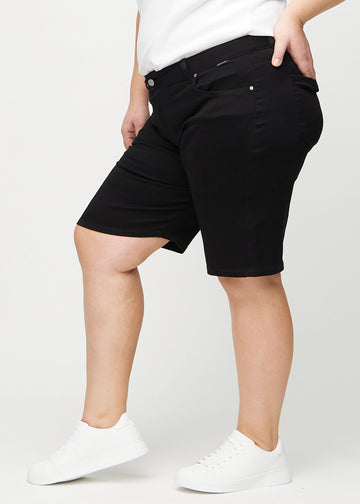 Schwarze regular Middle Shorts seitlich an einem Plus-Size-Model gezeigt.