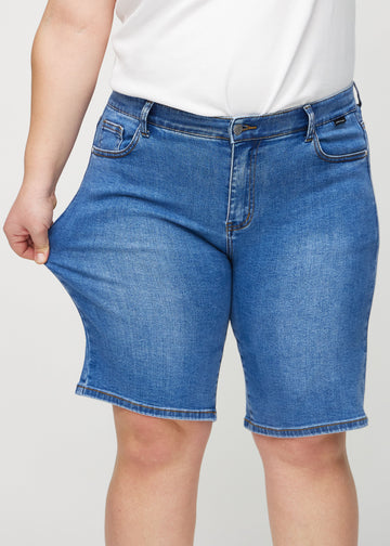 Das Plus-Size-Model zieht die Shorts am Oberschenkel auseinander, um den Stretch zu zeigen.