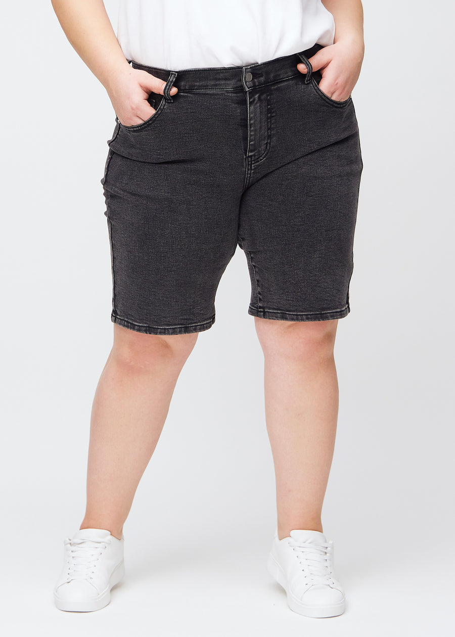 Dunkelgraue Denim-regular-Middle-Shorts, Modellname Shadows, die am Bein gerade nach unten verlaufen und knapp über dem Knie enden, an einem Plus-Size-Model, von vorne gesehen.