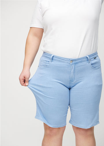 Das Plus-Size-Model zieht die Shorts am Oberschenkel auseinander, um den Stretch zu zeigen.