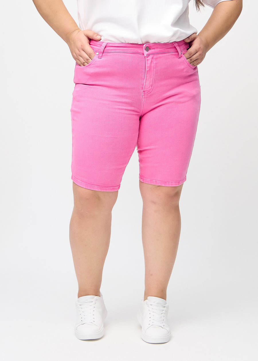 Hellrosa skinny middle shorts, Modellname Flamingos, die eng am Oberschenkel anliegen und bei einem Plus-Size-Model knapp über dem Knie enden, von vorne gesehen.