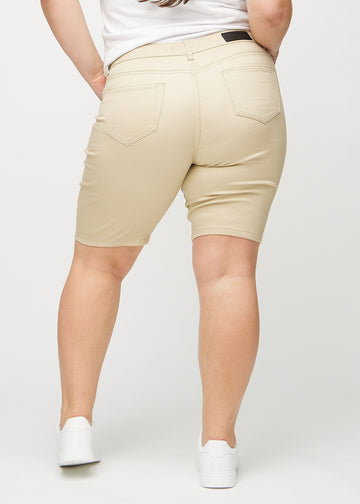 Beige skinny middle shorts von hinten an einem Plus-Size-Model, sodass das gesamte Produkt zu sehen ist.