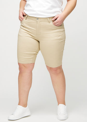 Beige skinny middle shorts, Modellname Gazelles, die eng am Oberschenkel anliegen und knapp über dem Knie enden, an einem Plus-Size-Model von vorne gesehen.