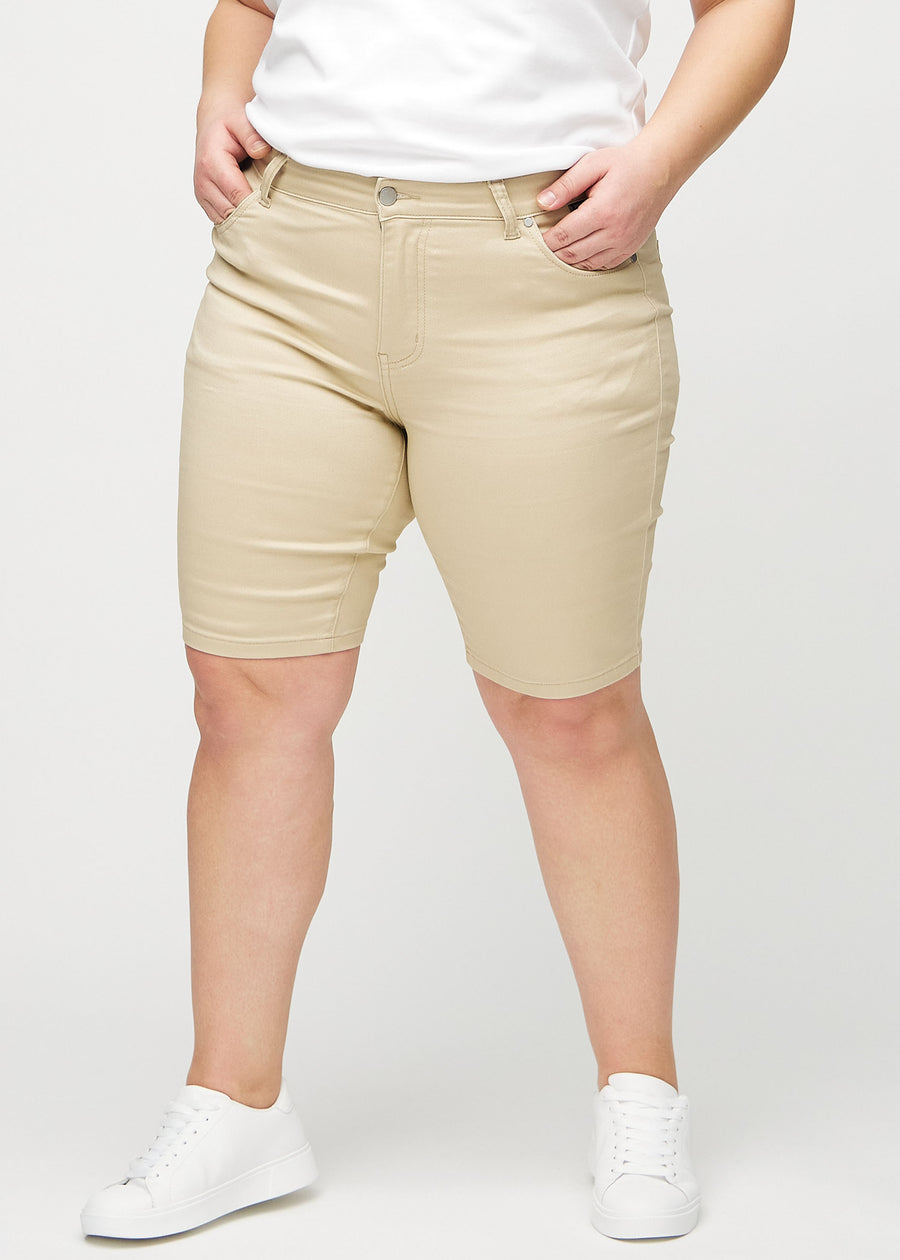Beige skinny middle shorts, Modellname Gazelles, die eng am Oberschenkel anliegen und knapp über dem Knie enden, an einem Plus-Size-Model von vorne gesehen.