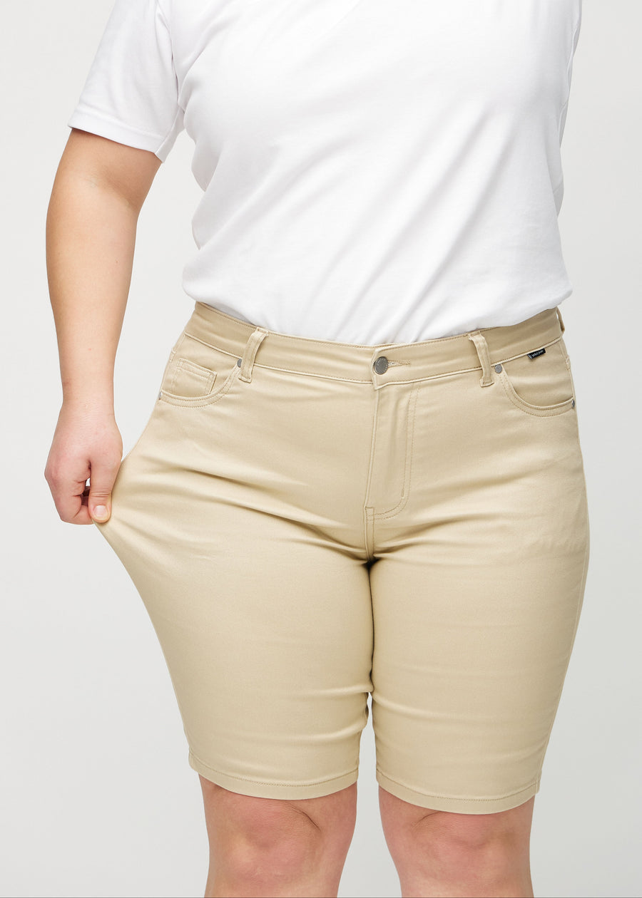 Das Plus-Size-Model zieht die Shorts am Oberschenkel auseinander, um den Stretch zu zeigen.