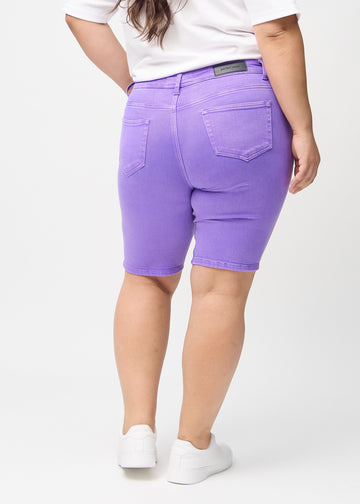 Lila skinny middle shorts von hinten an einem Plus-Size-Model gezeigt, sodass das gesamte Produkt zu sehen ist.