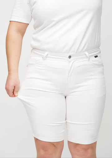 Das Plus-Size-Model zieht die Shorts am Oberschenkel auseinander, um den Stretch zu zeigen.
