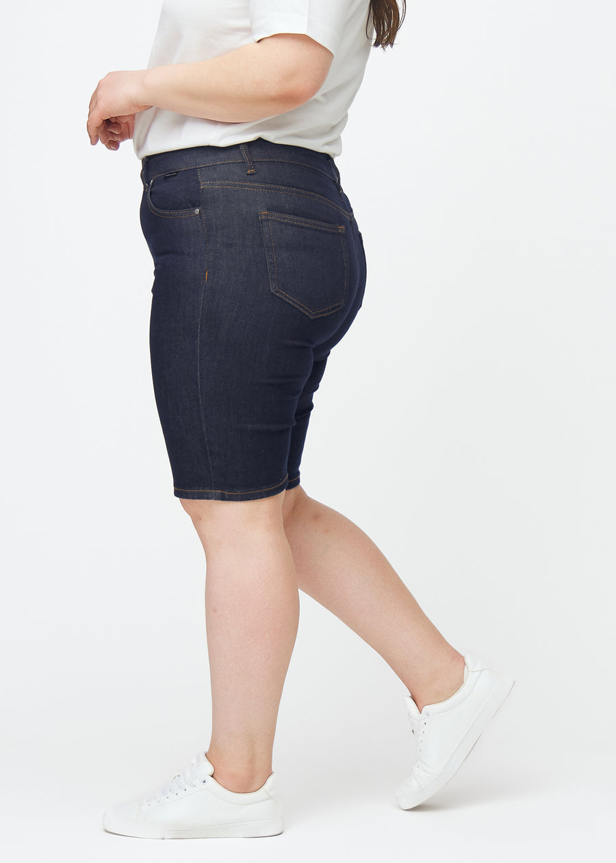 Tief dunkelblaue Denim-Shorts für Damen in der Farbe Midnights mit Skinny-Passform, von der Seite auf einem Plus-Size-Model gesehen.