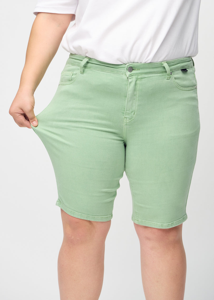 Das Plus-Size-Model zieht die Shorts am Oberschenkel, um den Stretch zu zeigen.