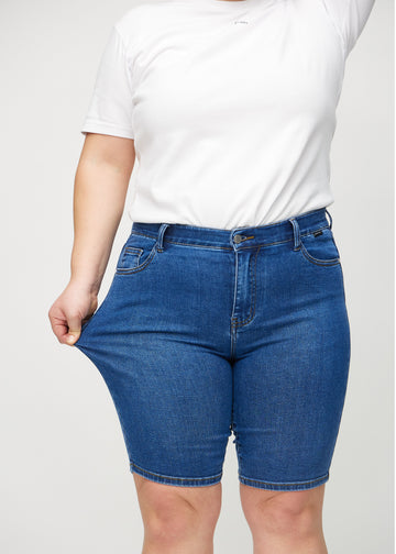 Das Plus-Size-Model zieht die Shorts am Oberschenkel auseinander, um den Stretch zu zeigen.