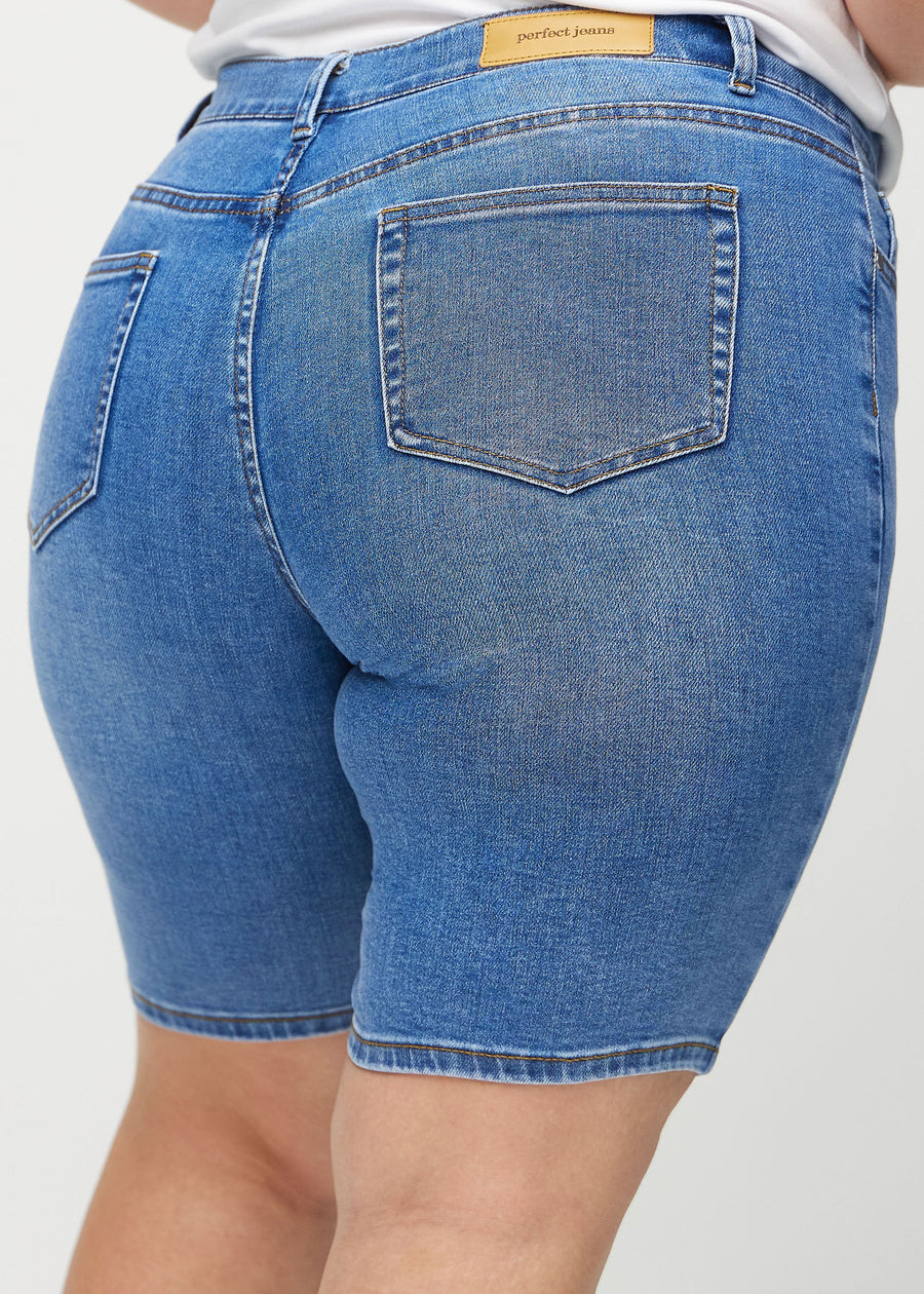 Denim skinny middle shorts von hinten in Nahaufnahme an einem Plus-Size-Model, um Details zu zeigen.