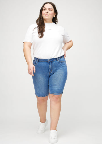 Ganzkörperbild eines Plus-Size-Models in Denim skinny middle shorts.