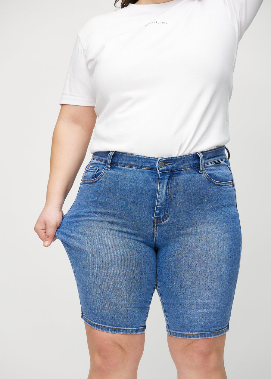 Das Plus-Size-Model zieht die Shorts am Oberschenkel auseinander, um den Stretch zu zeigen.