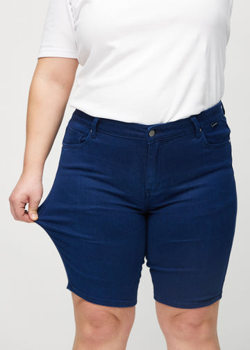 Das Plus-Size-Model zieht die Shorts am Oberschenkel auseinander, um den Stretch zu zeigen.