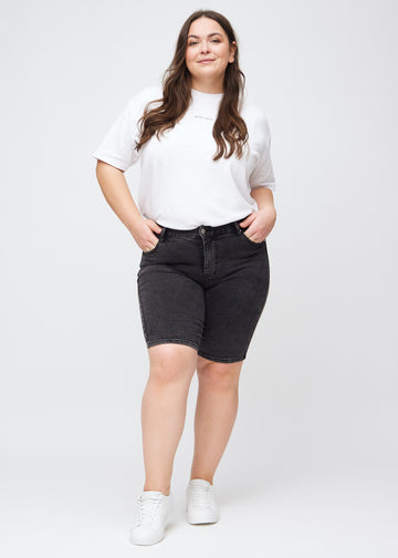 Ganzkörperbild eines Plus-Size-Models in dunkelgrauen Denim-skinny-Middle-Shorts.