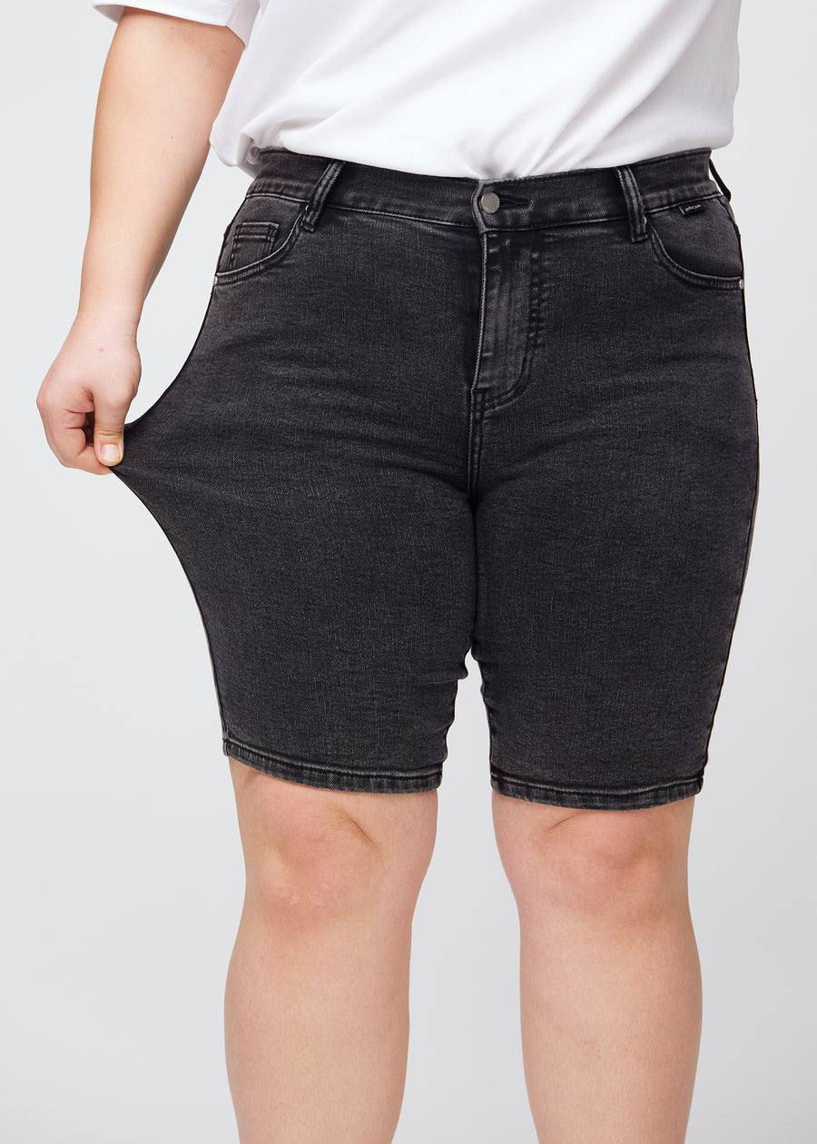 Das Plus-Size-Model zieht die Shorts am Oberschenkel auseinander, um den Stretch zu zeigen.