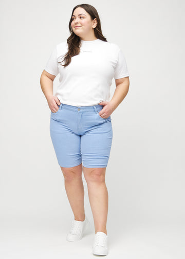 Ganzkörperbild eines Plus-Size-Models in hellblauen skinny middle shorts.