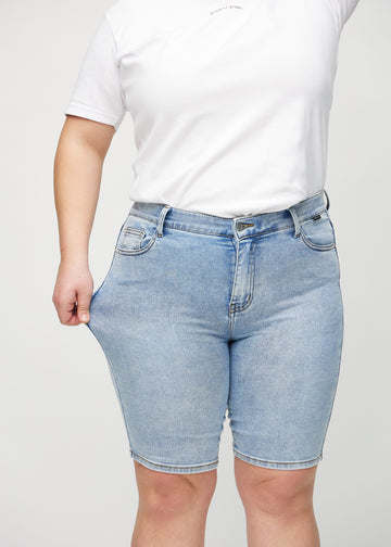 Das Plus-Size-Model zieht die Shorts am Oberschenkel auseinander, um den Stretch zu zeigen.
