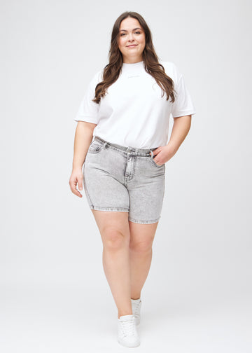 Ganzkörperbild eines Plus-Size-Models in hellgrauen Denim-skinny-Short Shorts.