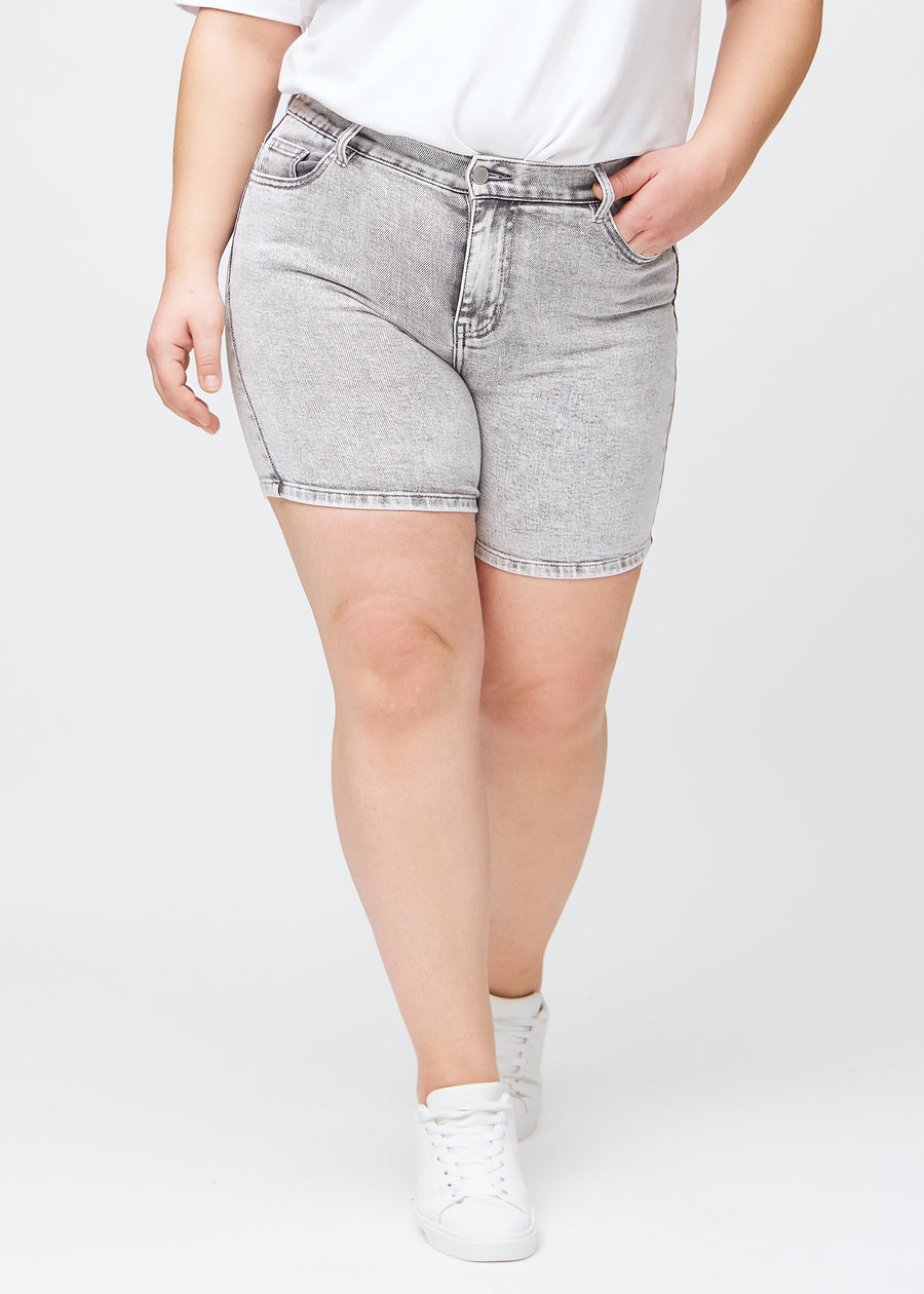 Hellgraue Denim-skinny-Short Shorts, Modellname Ashes, die eng anliegen und bei einem Plus-Size-Model bis zur Mitte des Oberschenkels reichen, von vorne gesehen.