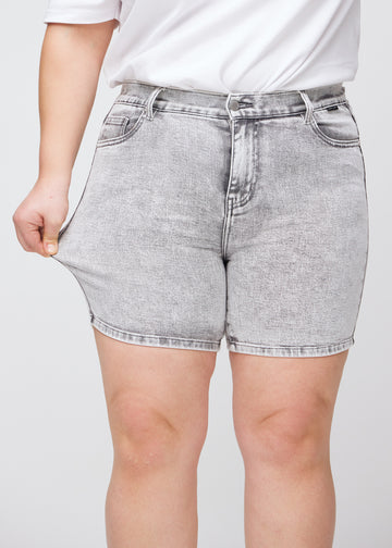 Das Plus-Size-Model zieht die Shorts am Oberschenkel auseinander, um den Stretch zu zeigen.