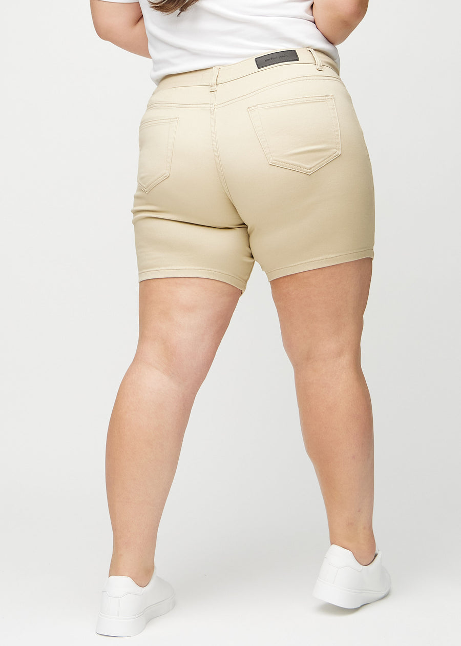Beige skinny Short Shorts von hinten an einem Plus-Size-Model gezeigt, damit das gesamte Produkt zu sehen ist.