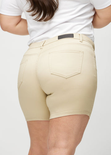 Beige skinny Short Shorts von hinten in Nahaufnahme an einem Plus-Size-Model gezeigt, um Details zu zeigen.