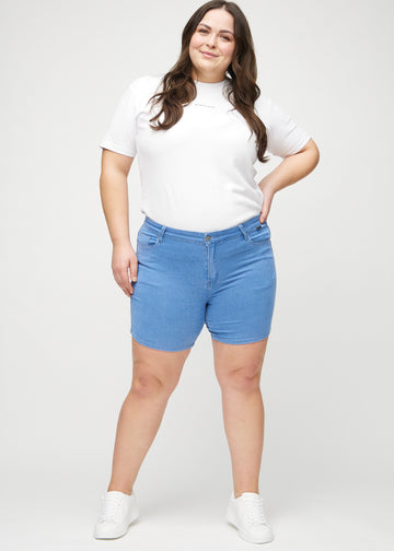 Ganzkörperbild eines Plus-Size-Models in blauen skinny Short Shorts.
