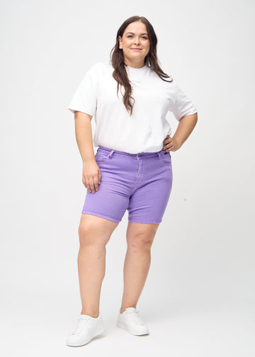 Ganzkörperbild eines Plus-Size-Models in lila skinny Short Shorts.