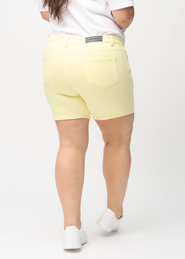 Hellgelbe skinny Short Shorts von hinten an einem Plus-Size-Model gesehen, sodass man das gesamte Produkt sehen kann.
