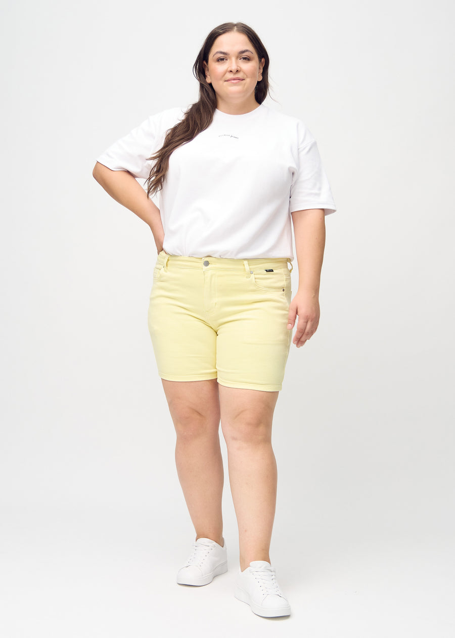 Ganzkörperbild eines Plus-Size-Models in hellgelben skinny Short Shorts.