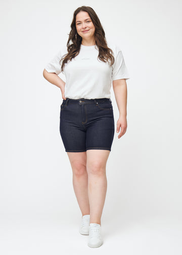 Ganzkörperbild eines Plus-Size-Models in tief dunkelblauen Denim-Shorts für Damen in der Farbe Midnights mit Skinny-Passform.