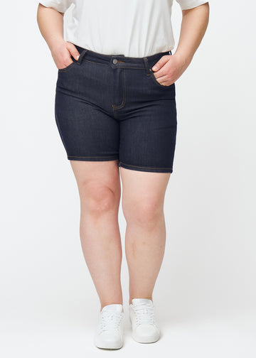 Tief dunkelblaue Denim-Shorts für Damen in der Farbe Midnights mit Skinny-Passform, von vorne auf einem Plus-Size-Model gesehen.