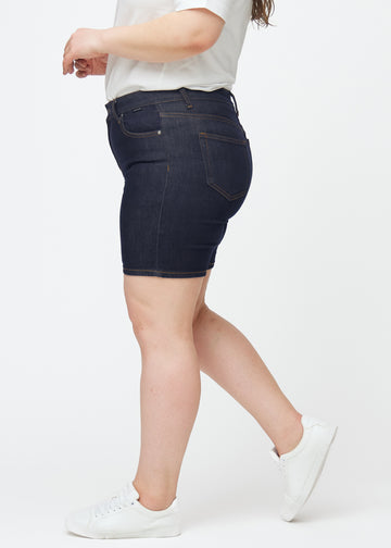 Tief dunkelblaue Denim-Shorts für Damen in der Farbe Midnights mit Skinny-Passform, von der Seite auf einem Plus-Size-Model gesehen.