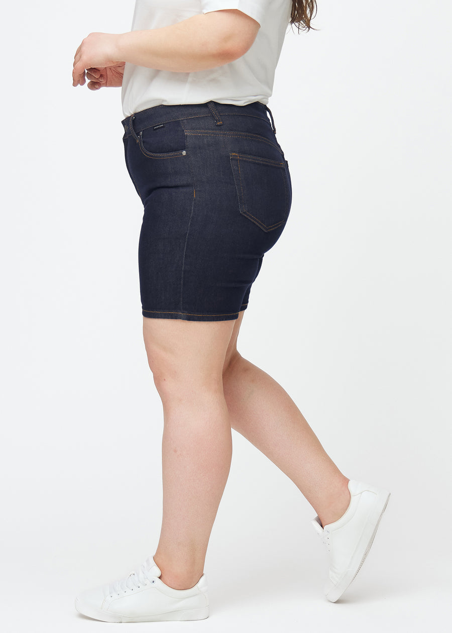 Tief dunkelblaue Denim-Shorts für Damen in der Farbe Midnights mit Skinny-Passform, von der Seite auf einem Plus-Size-Model gesehen.