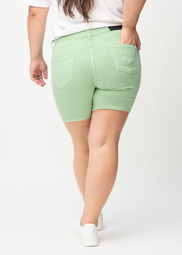 Hellgrüne skinny Short Shorts von hinten an einem Plus-Size-Model gesehen, sodass das gesamte Produkt sichtbar ist.