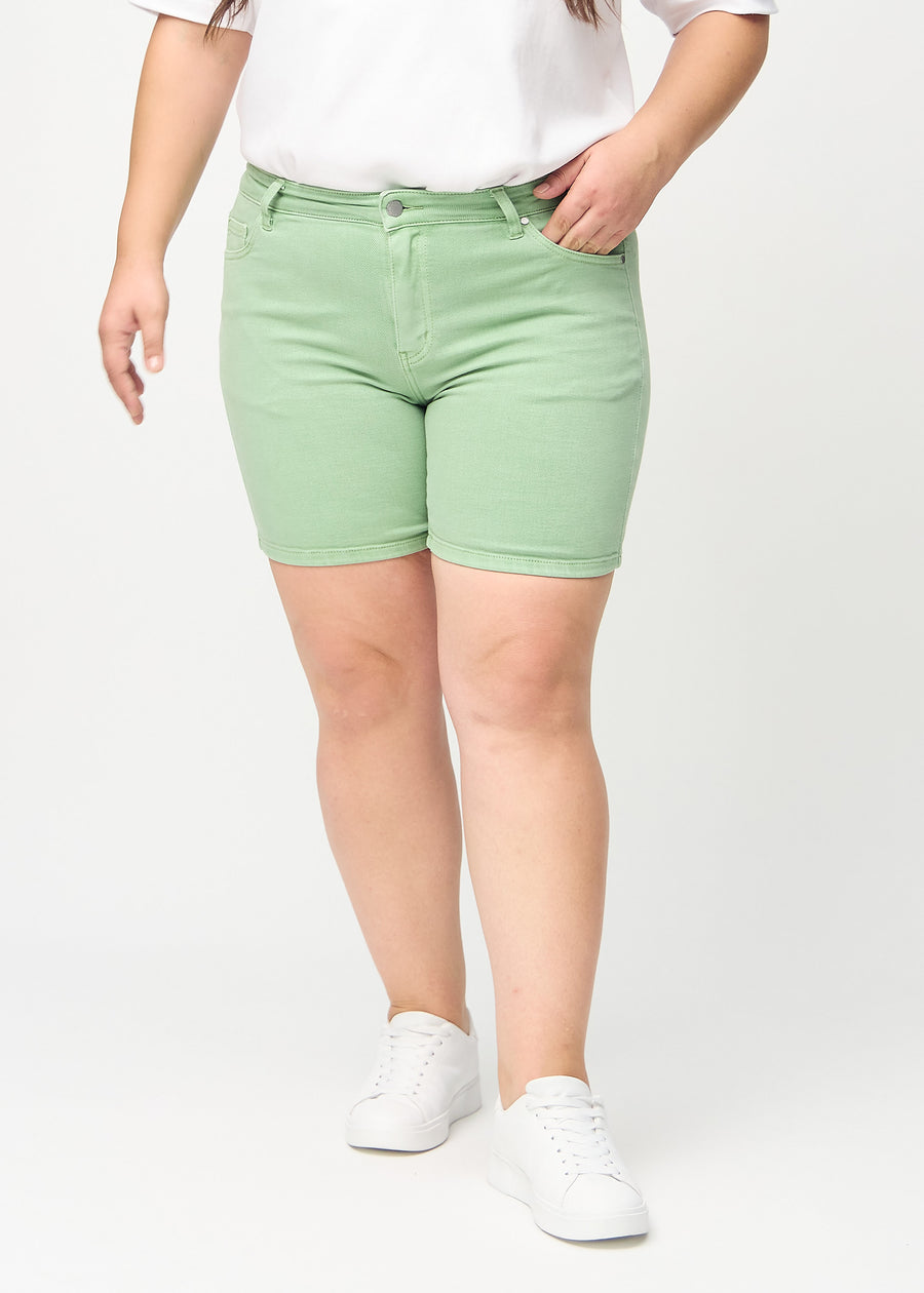 Hellgrüne skinny Short Shorts, Modellname Mints, die eng anliegen und bei einem Plus-Size-Model bis zur Mitte des Oberschenkels reichen, von vorne gesehen.