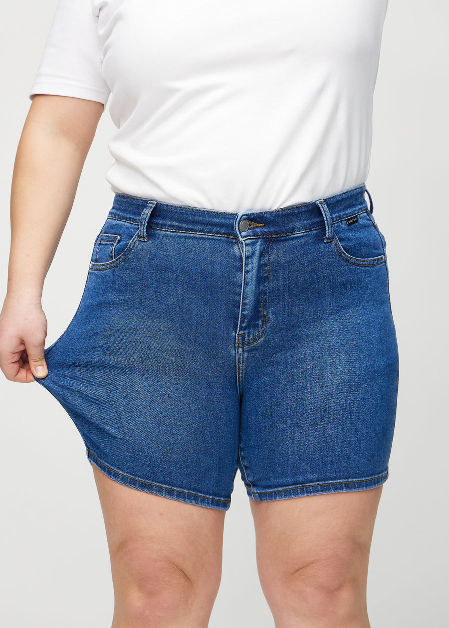 Das Plus-Size-Model zieht die Shorts am Oberschenkel auseinander, um den Stretch zu zeigen.