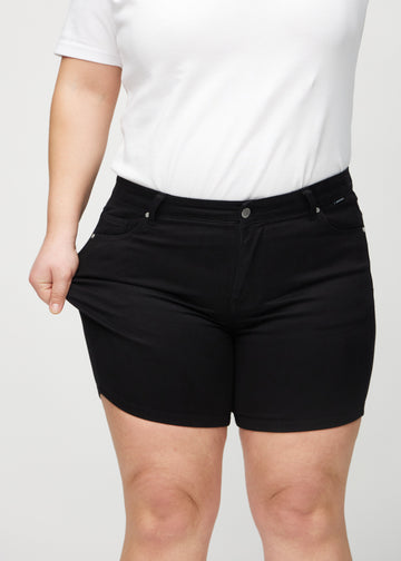 Das Plus-Size-Model zieht die Shorts am Oberschenkel auseinander, um den Stretch zu zeigen.